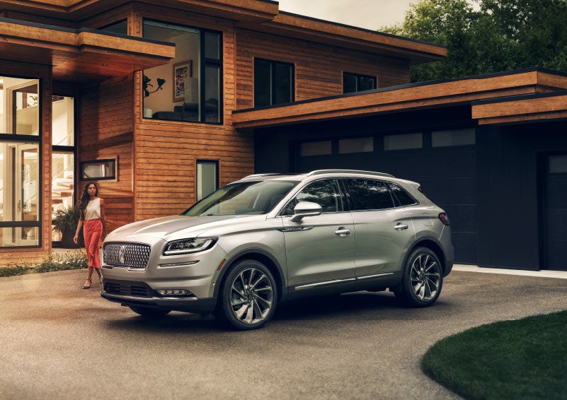 A person is shown approaching a 2023 Lincoln Nautilus® SUV that is parked in a driveway.